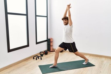 Young arab man smiling confident training yoga at sport center