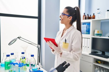 Genç ve güzel İspanyol bilim kadını. Laboratuvarda dokunmatik ped kullanarak gülümsüyor.