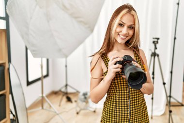 Beyaz kadın fotoğrafçı profesyonel fotoğraf stüdyosunu tutuyor.