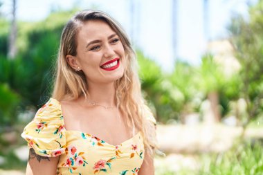 Genç, güzel, İspanyol bir kadın, gülümsüyor. Parkta kendine güveniyor.