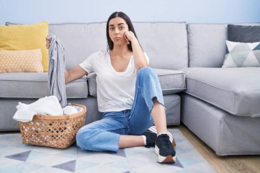 Young brunette woman doing laundry at home depressed and worry for distress, crying angry and afraid. sad expression. 