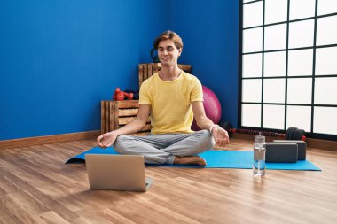 Young caucasian man smiling confident having online yoga class at sport center