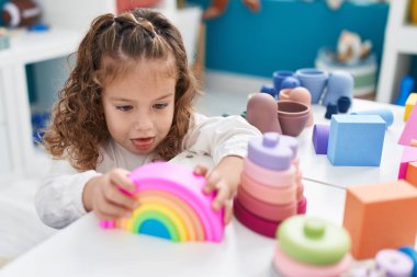 Sevimli sarışın çocuk anaokulundaki masada oyuncaklarla oynuyor.
