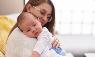 Mother and son hugging each other sitting on sofa at home