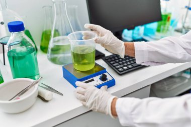 Laboratuvarda beyaz saçlı, bilim adamı üniforması giyen yaşlı bir kadın.