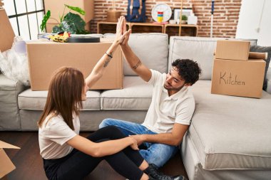 Erkek ve kadın çift gülümsüyor. Kendine güvenen bir beşlik. Yeni evlerinde eller havada.