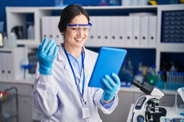 Young woman scientist using touchpad at laboratory