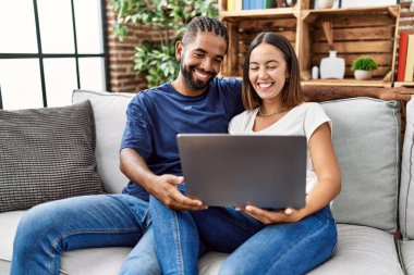 Man and woman couple using laptop hugging each other at home