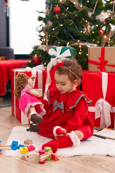 愛らしいヒスパニック系幼児遊びますおもちゃで床に座っていますクリスマスプレゼントによって家 — ストック写真