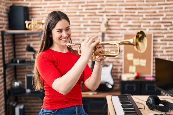 Young woman musician playing trumpet at music studio