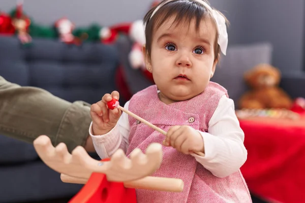 愛らしいヒスパニック赤ちゃん遊びとともにトナカイロッキングによってクリスマス装飾で家 — ストック写真