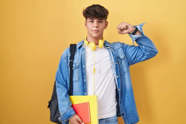 西班牙裔青少年背着学生背包 拿着书 强壮有力地展示了臂膀肌肉 自信而自豪 — 图库照片