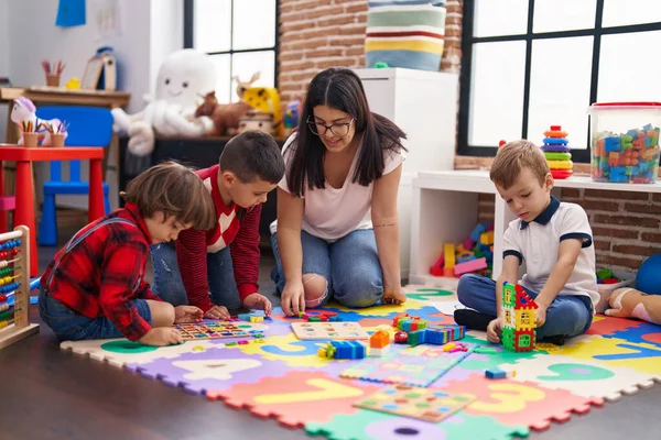 幼儿园的老师和一群男孩子坐在地板上玩数学拼图游戏 — 图库照片