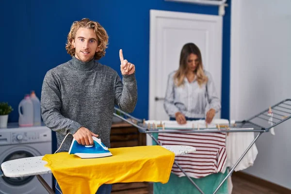 Couple Ironing Clothes Laundry Room Surprised Idea Question Pointing Finger — Stockfoto