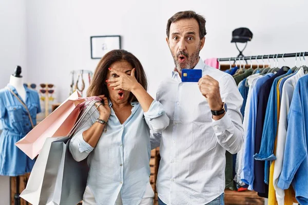 Hispanic Middle Age Couple Holding Shopping Bags Credit Card Peeking — Stockfoto