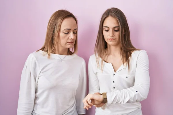 Middle Age Mother Young Daughter Standing Pink Background Checking Time — Stock Photo, Image