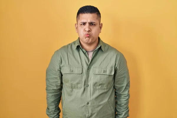 Hispanic Young Man Standing Yellow Background Puffing Cheeks Funny Face — Photo