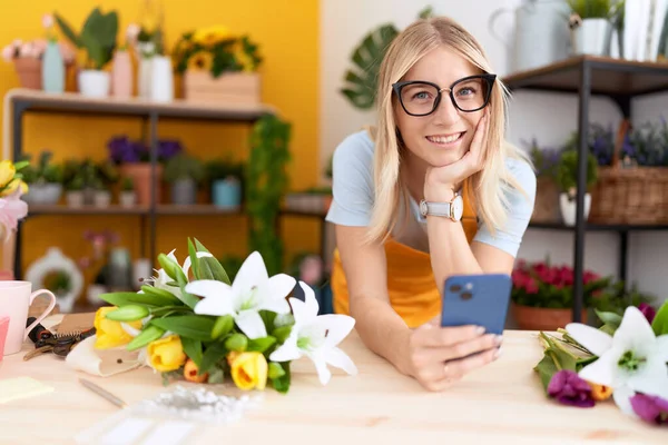 Young Blonde Woman Florist Using Smartphone Leaning Table Flower Shop — Fotografia de Stock