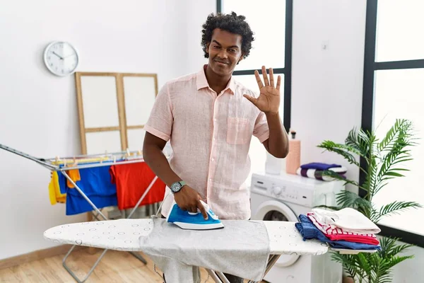 African Man Curly Hair Ironing Clothes Home Waiving Saying Hello — Stock fotografie