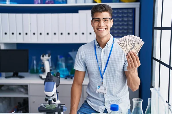 科学研究所で働いている若いヒスパニック系の男は 肯定的で幸せな立場を見て 歯を示す自信を持って笑顔で笑っています — ストック写真