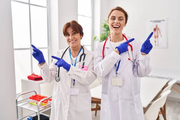 Dos Mujeres Vistiendo Uniforme Médico Estetoscopio Sonriendo Mirando Cámara Apuntando — Foto de Stock