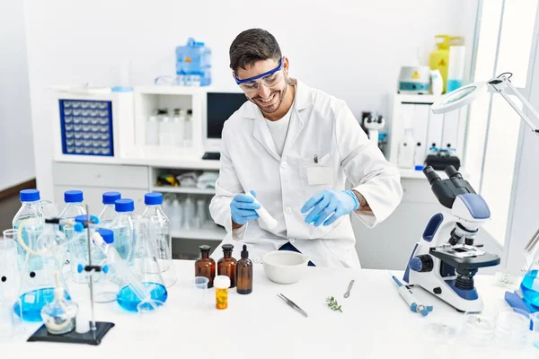 Laboratuvarda bilimsel havan topu kullanan yakışıklı İspanyol.