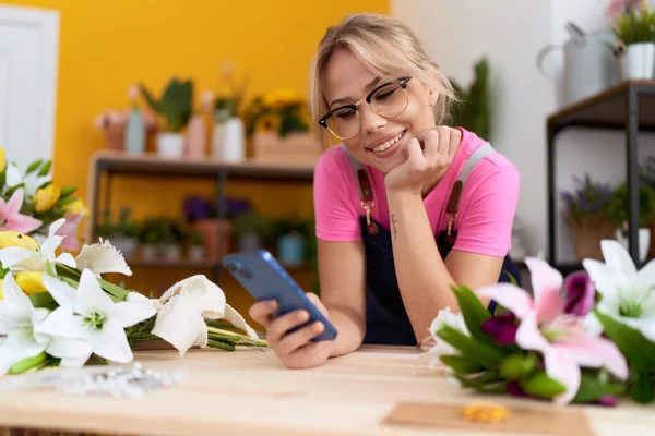 Young Blonde Woman Florist Using Smartphone Leaning Table Flower Shop —  Fotos de Stock