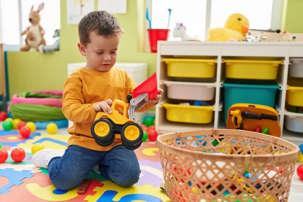 愛らしいです白人男の子遊びますトラクターおもちゃで床に座って幼稚園 — ストック写真