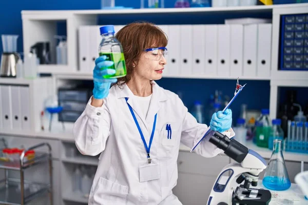 研究室で瓶読み文書を保持する中年女性科学者 — ストック写真
