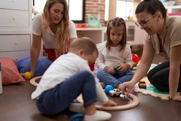教師と男の子と女の子遊び車おもちゃで床の上に座って幼稚園 — ストック写真