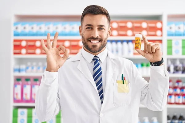 Handsome Hispanic Man Working Pharmacy Drugstore Holding Pills Doing Sign — Stockfoto