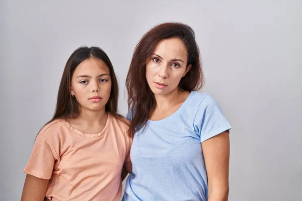 Young mother and daughter standing over white background looking sleepy and tired, exhausted for fatigue and hangover, lazy eyes in the morning.