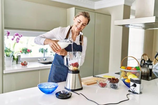 Genç Sarışın Kadın Mutfaktaki Miksere Süt Dökerek Gülümsüyor — Stok fotoğraf