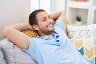 Young man relaxed with hands on head sitting on sofa at home