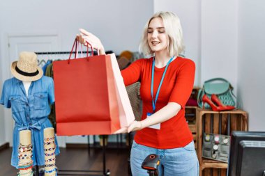 Giysi dükkanında kendine güvenen, gülümseyen beyaz bir kadın.