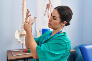 Genç, güzel İspanyol kadın pisiyoterapist rehabilitasyon kliniğinde bilek ağrısı çekiyor.