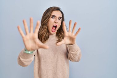 Arka planda korkmuş ve dehşete düşmüş genç bir kadın. El hareketlerini durdur, şok içinde bağır. panik konsepti. 