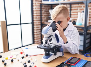 Sınıfta mikroskop kullanan sevimli bir çocuk.