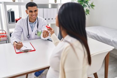 Genç latin çift doktor ve hasta klinikte idrar testi tüpü tutarak tıbbi seans yapıyorlar.