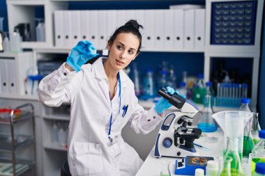 Young caucasian woman scientist using microscope looking sample at laboratory