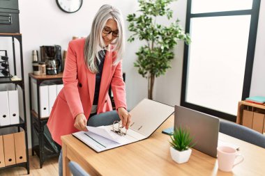 Ofiste çalışan, orta yaşlı, kır saçlı iş kadını.