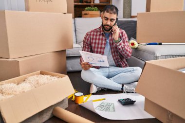 Genç İspanyol adam yeni evinde akıllı telefon okuyarak konuşuyor.