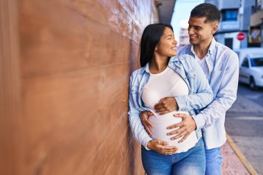 Genç Latin çift sokakta karnına dokunacak bir bebek bekliyor.
