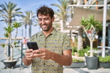 Sokakta akıllı telefon kullanan, kendine güvenen genç bir İspanyol.