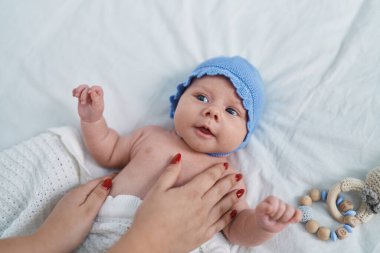 Adorable caucasian baby lying on bed with relaxed expression at bedroom