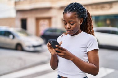 Sokakta akıllı telefon kullanan Afro-Amerikalı kadın.