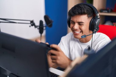 Oyun odasında akıllı telefon kullanarak video oyunu oynayan İspanyol asıllı genç adam.