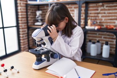 Laboratuvar sınıfında mikroskop kullanan sevimli İspanyol kız öğrenci.