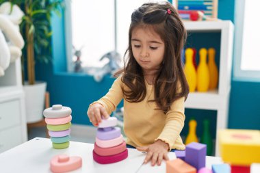 Anaokulundaki masada oturan, inşaat bloklarıyla oynayan sevimli İspanyol kız.