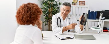 Doktor üniforması giyen orta yaşlı bir adam ve kadın klinikte tıbbi danışmanlık yapıyorlar.